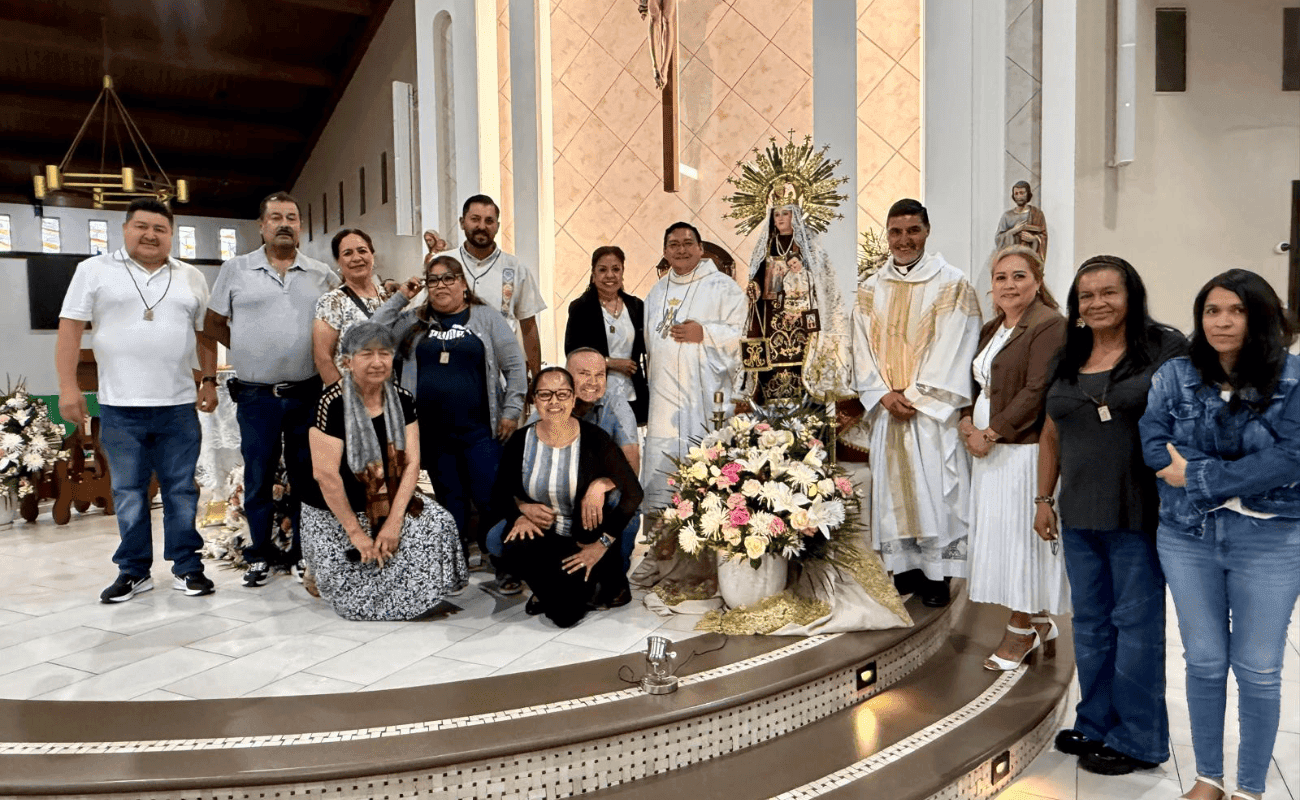 Parishioners and priests beside a religious image adorned with flowers on the altar