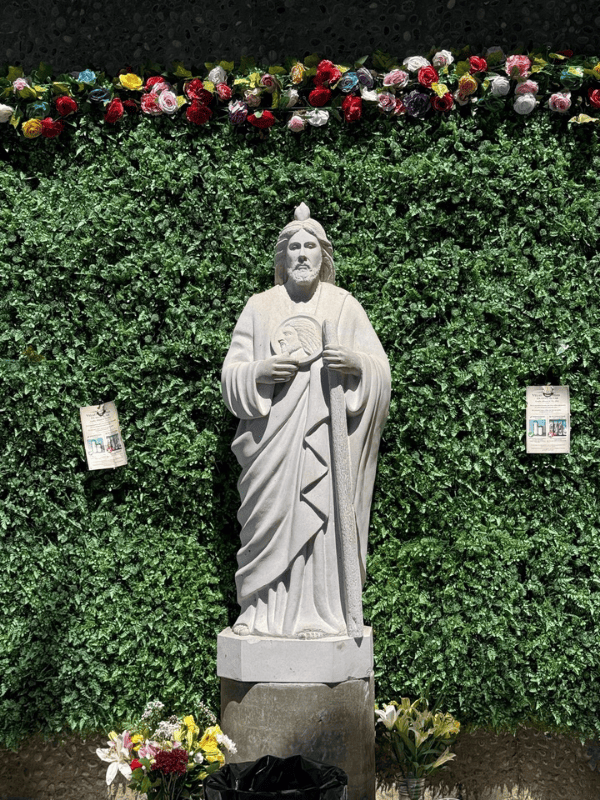 Statue of Christ beside a hedge and flowers