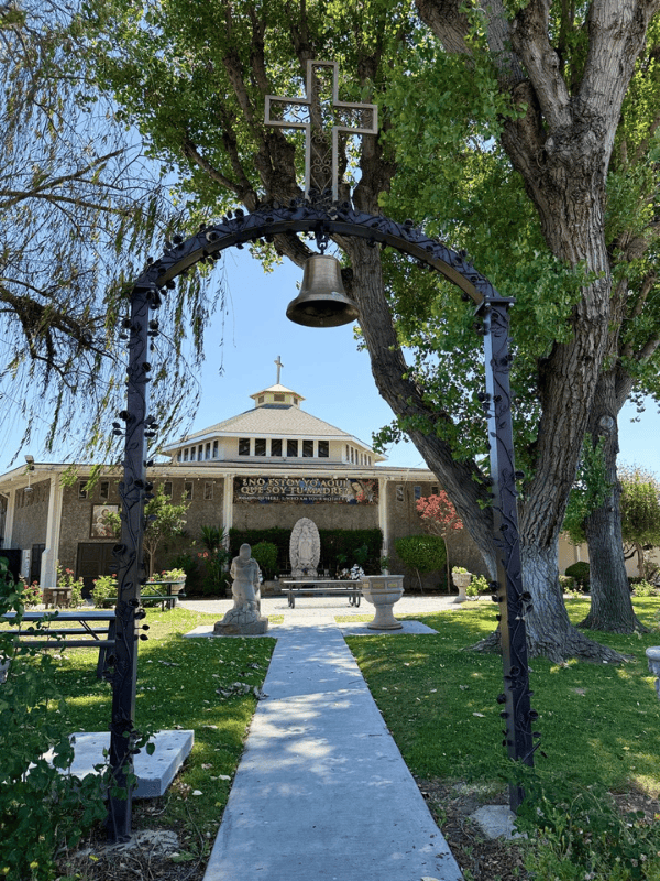 Garden path with an archway and bell leading to the church