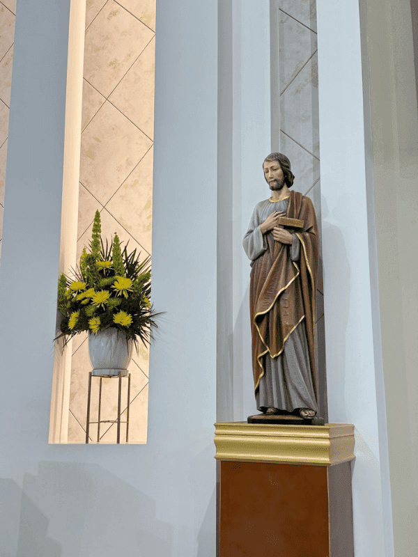 Statue of a saint with yellow flowers inside the church